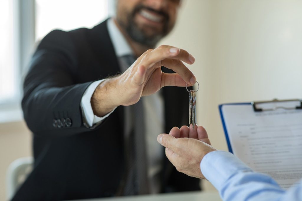 A solicitor handing a set of house keys across a desk to a client