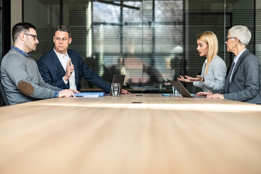 Four colleagues in discussion around a boardroom table