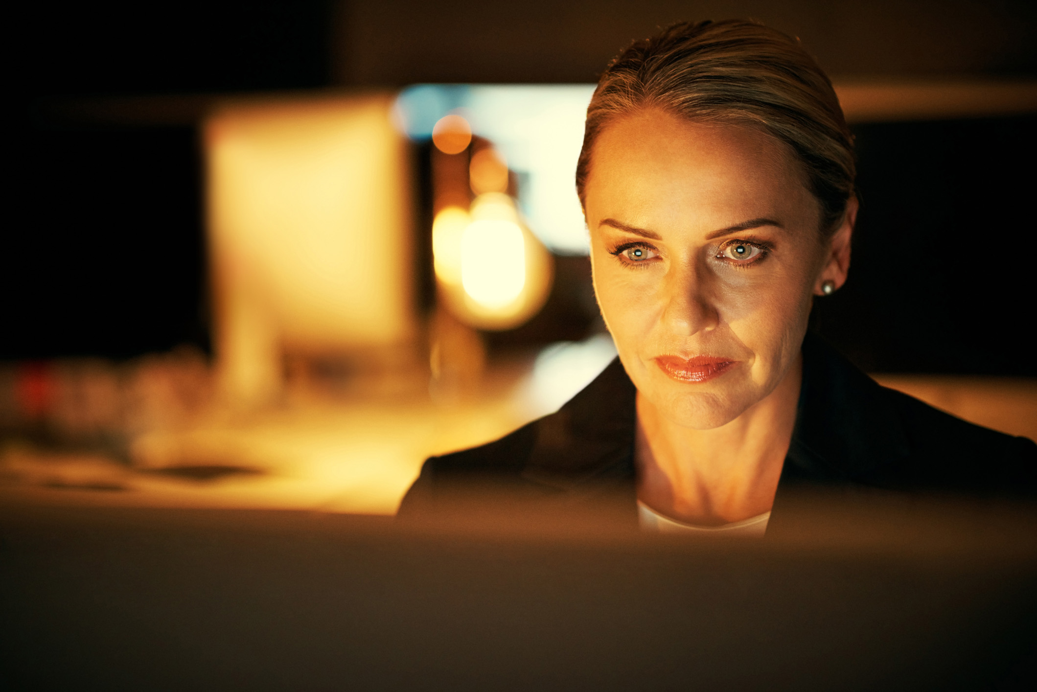 A woman working at a computer screen in a darkened office